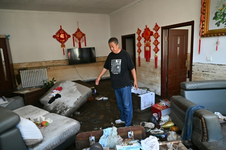 Monsieur Wang, 57 ans, montre sa maison endommagée par les inondations après les récentes inondations dans le district de Huairou, en banlieue de Pékin ( AFP / Pedro Pardo )