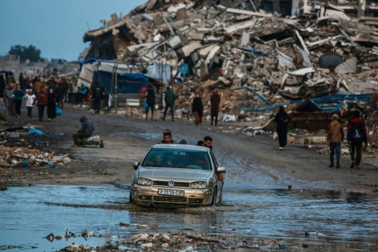 Un homme conduit une voiture sur la voie inondée d'un quartier de Jabalia, dans le nord de la bande de Gaza, le 10 décembre 2025 ( AFP / BASHAR TALEB )