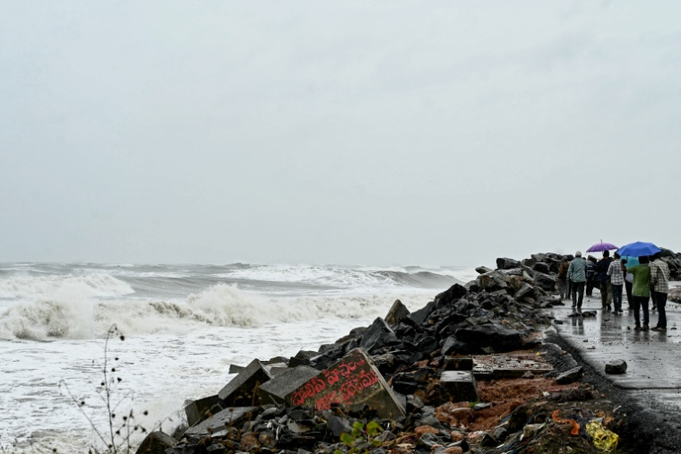 Des passants le long de la côte du golfe du Bengale, à Kakinada, en Inde, le 27 octobre 2026, avant le passage attendu du cyclone Arnab ( AFP / NOAH SEELAM )