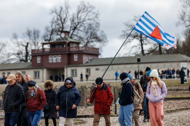 Des personnes devant la porte principale du camp nazi de Buchenwald avant une cérémonie de commémoration marquant le 80e anniversaire de la libération du camp de concentration nazi de Buchenwald, près de Weimar, dans l'est de l'Allemagne, le 6 avril 2025 ( AFP / JENS SCHLUETER )