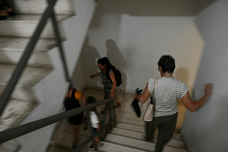 Des employés dévalent les escaliers après une secousse provoquée par un séisme de magnitude 6,5 à La Havane, le 8 juin 2026 à Cuba ( AFP / YAMIL LAGE )