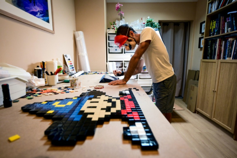 Le street-artiste In The Woup travaille sur une mosaïque inspirée de l'univers "Super Mario", dans son studio à Lyon, le 28 août 2025 ( AFP / OLIVIER CHASSIGNOLE )