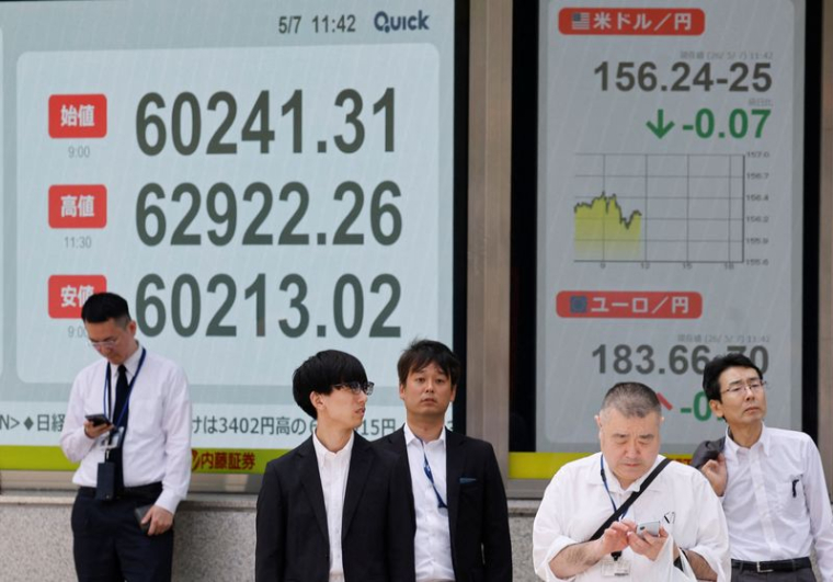 Des piétons passent devant un tableau de cotation boursière indiquant la moyenne des actions Nikkei à l'extérieur d'une maison de courtage à Tokyo