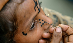 Un tatouage traditionnel est dessiné sur le visage de la jeune Champa, 7 ans, à la colonie Jogi à Umerkot, un district à majorité hindoue, le 14 juillet 2025 au Pakistan ( AFP / Asif HASSAN )
