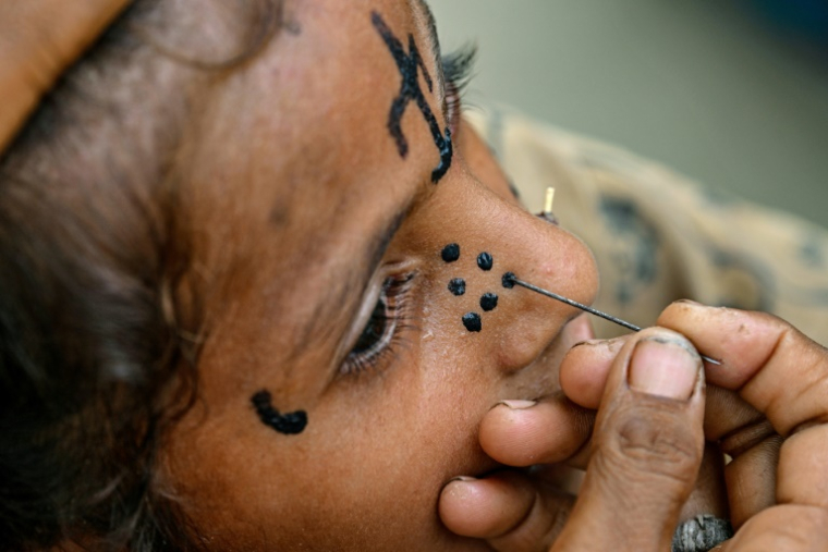 Un tatouage traditionnel est dessiné sur le visage de la jeune Champa, 7 ans, à la colonie Jogi à Umerkot, un district à majorité hindoue, le 14 juillet 2025 au Pakistan ( AFP / Asif HASSAN )