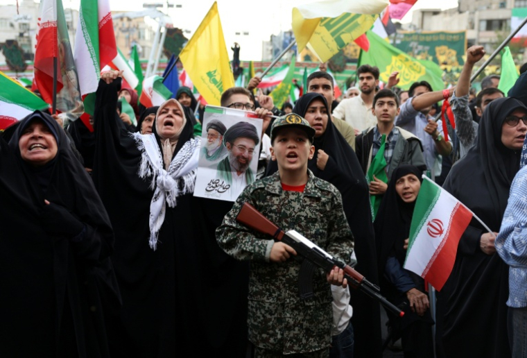 Un jeune Iranien en uniforme militaire brandit un fusil factice lors d'un rassemblement des partisans du pouvoir, le 29 avril 2029 à Téhéran ( AFP / - )