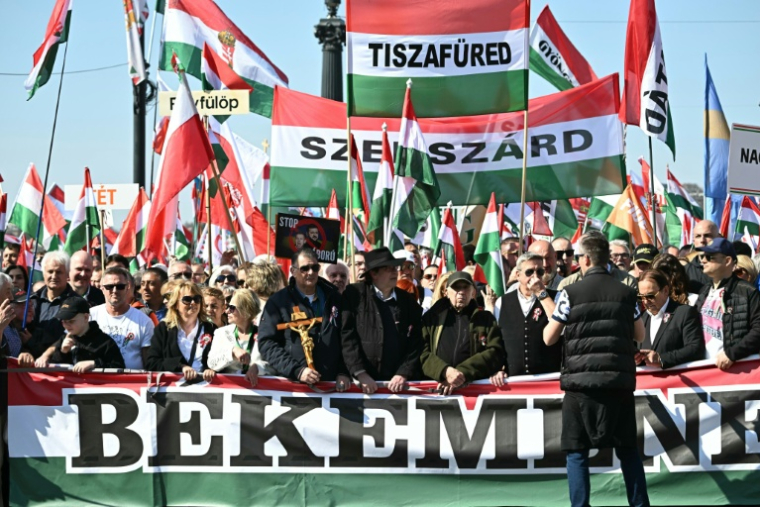 Des manifestants brandissent des drapeaux hongrois, des banderoles et des croix lors d'une marche de soutien au parti Fidesz du Premier ministre hongrois Vitkor Orban, le 15 mars 2026 à Budapest ( AFP / Attila KISBENEDEK )