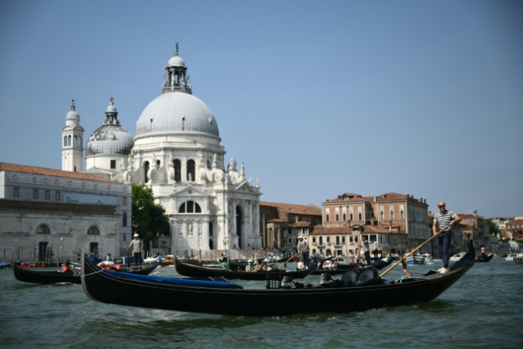 Des gondoliers naviguent sur le Grand Canal dans la lagune de Venise le 25 juin 2025, où le mariage de Jeff Bezos et de Lauren Sanchez irritent certains habitants ( AFP / Marco BERTORELLO )