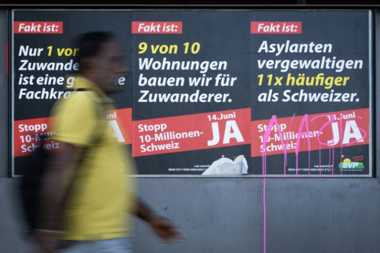 Un homme passe devant des affiches appelant à voter "oui" lors de l'initiative du 14 juin prochain pour plafonner la population à 10 millions, une proposition anti-immigration, à Zurich, le 28 mai 2026 ( AFP / SEBASTIEN BOZON )
