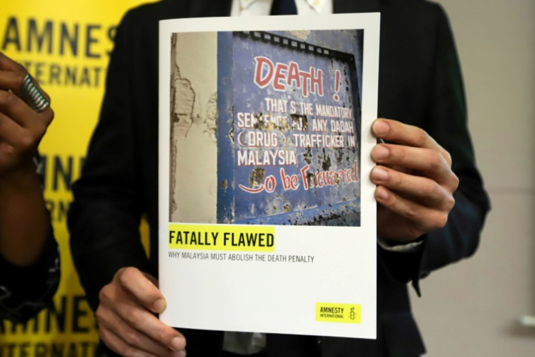 Un membre d'Amnesty International montre un rapport sur la peine de mort en Malaisie, le 10 octobre 2019 à Petaling Jaya ( AFP / SADIQ ASYRAF )