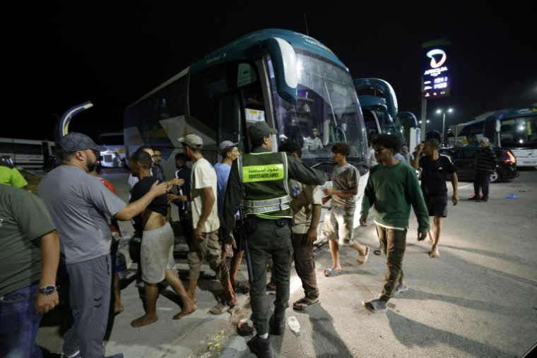 Des membres des forces de l'ordre marocaines acheminent par bus vers leurs villes d'origine des personnes qui avaient pénétré illégalement dans l'enclave espagnole de Ceuta, sur la côte nord du Maroc, le 1er août 2026 à Fnideq ( AFP / Abdel Majid BZIOUAT )