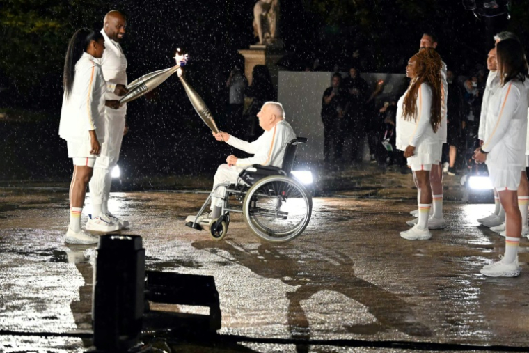 Charles Coste remettait la flamme olympique aux derniers porteurs Teddy Riner et Marie-José Pérec, lors de la cérémonie d'ouverture des Jeux de Paris 2024 le 26 juillet 2024, au Jardin des Tuileries ( AFP / MOHD RASFAN )
