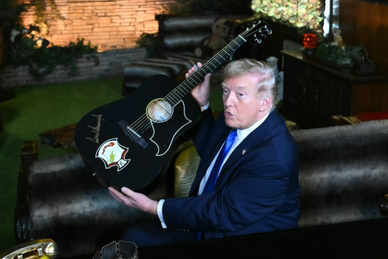 Le président américain Donald Trump montre la réplique d'une guitare d'Elvis Presley après l'avoir signée, le 23 mars 2026 lors d'une visite à Graceland, dans le Tennessee ( AFP / SAUL LOEB )
