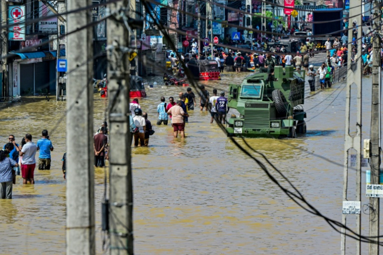 Des fils endommagés pendent des poteaux électriques tandis qu'un camion militaire traverse une rue inondée après de fortes pluies à Wellampitiya, en périphérie de Colombo, la capitale du Sri Lanka, le 30 novembre 2025 ( AFP / Ishara S. KODIKARA )