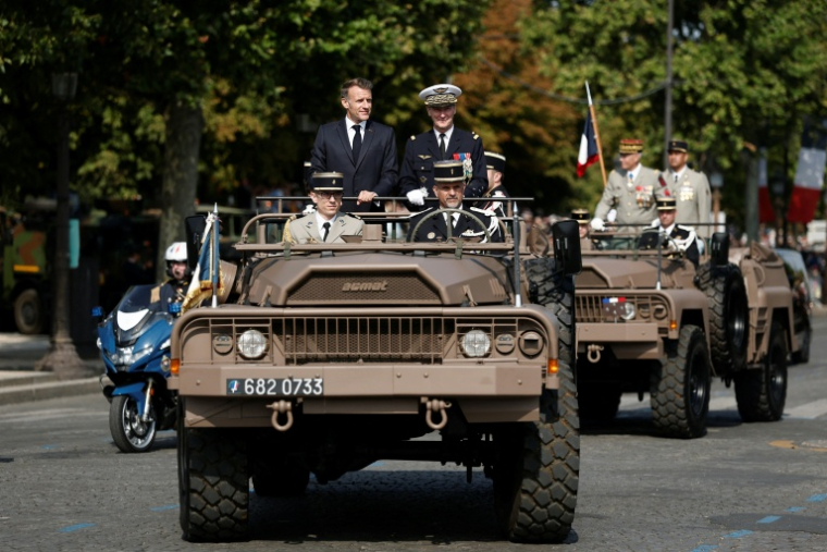 FLe président Emmanuel Macron (c) à bord du véhicule de commandement aux côtés du chef d'état-major des armées Fabien Mandon (c,d) lors du défilé militaire annuel sur l'avenue des Champs-Élysées à Paris, le 14 juillet 2026 ( POOL / Benoit Tessier )