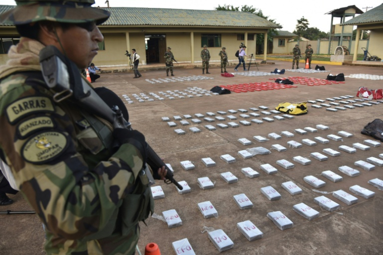Des membres de la Force spéciale de lutte contre le trafic de drogue (FELCN) de Bolivie montent la garde devant 582 kg de chlorhydrate de cocaïne, saisis dans un ranch — où la drogue devait apparemment être raffinée — dans la localité de Guayaramerín, à la frontière nord-est avec le Brésil, le 17 avril 2018 ( ar / AIZAR RALDES )