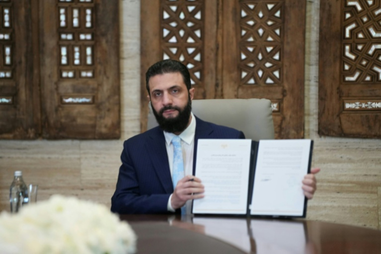 Le président syrien Ahmad al-Chareh montre un accord de cessez-le-feu signé à distance avec le chef des forces kurdes, le 18 janvier 2026 au palais présidentiel de Damas. ( AFP / Rami al SAYED )