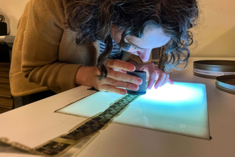 Courtney Holschuh utilise une loupe pour regarder la pellicule d'un film, au Centre national de conservation audiovisuelle de la Bibliothèque du Congrès à Culpeper, le 2 avril 2026 en Virginie ( AFP / Kent Nishimura )
