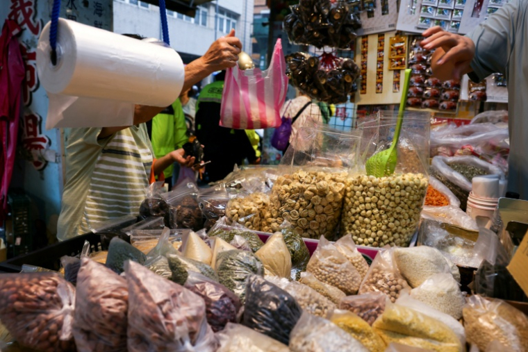 Un commerçant met des produits dans un sac en plastique sur un marché traditionnel de Keelung, à Taïwan, le 9 juin 2026 ( AFP / I-Hwa Cheng )