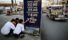 Des employés changent le prix des carburants dans une station-service de Manille, le 17 mars 2026 aux Philippines ( AFP / Ted ALJIBE )