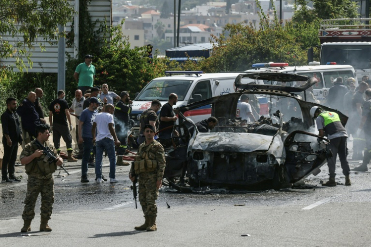 Des secouristes autour d'un véhicule ciblé par une frappe de drone israélien sur une autoroute près de la ville de Jiyeh, au sud de Beyrouth, le 13 mai 2026 au Liban ( AFP / MAHMOUD ZAYYAT )