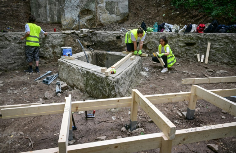 Des étudiants en architecture participent à la reconstruction d'une promenade de la cité thermale de Baile Herculane, le 29 juillet 2025 en Roumanie ( AFP / Daniel MIHAILESCU )