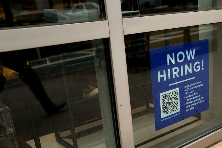 Un panneau d'embauche est visible dans la vitrine d'une entreprise aux États-Unis