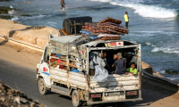 Des déplacés palestiniens fuyant le nord de la bande de Gza en direction du sud du terrtoire roulent à bord d'un camion chargé d'effets personnels sur la route côtière du camp de Nousseirat (centre), le 30 août 2025 ( AFP / Eyad BABA )