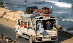 Des déplacés palestiniens fuyant le nord de la bande de Gza en direction du sud du terrtoire roulent à bord d'un camion chargé d'effets personnels sur la route côtière du camp de Nousseirat (centre), le 30 août 2025 ( AFP / Eyad BABA )