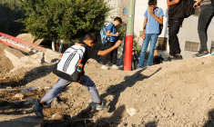 Des étudiants palestiniens traversent une barrière de terre israélienne sur le chemin de l'école à Araqah