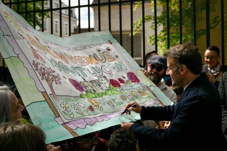 Le président Emmanuel Macron signe un dessin réalisé par des écolisiers à Montluçon, le 22 avril 2026 dans l'Allier ( POOL / Jeff PACHOUD )