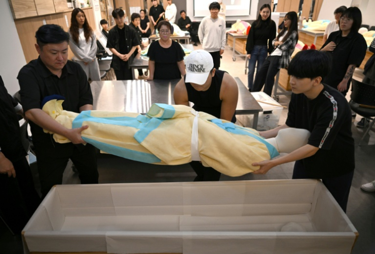 Des étudiants s'entraînent sur un mannequin au rite de la mise en bière dans une salle de classe de l'Institut des sciences et technologies de Busan, dans le sud-est de la Corée du Sud, le 24 septembre 2025 ( AFP / Jung Yeon-je )