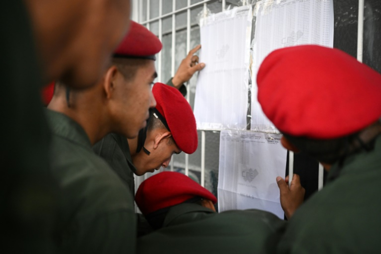 Des membres de la garde d'honneur vérifient les listes électorales avant de voter lors des élections régionales dans un bureau de vote à Caracas le 25 mai 2025 ( AFP / Federico PARRA )