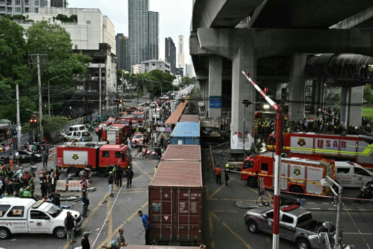 Des pompiers et secouristes sur le site d'une collision entre un train de marchandises et un bus à Bangkok, le 16 mai 2026 en Thaïlande ( AFP / Lillian SUWANRUMPHA )
