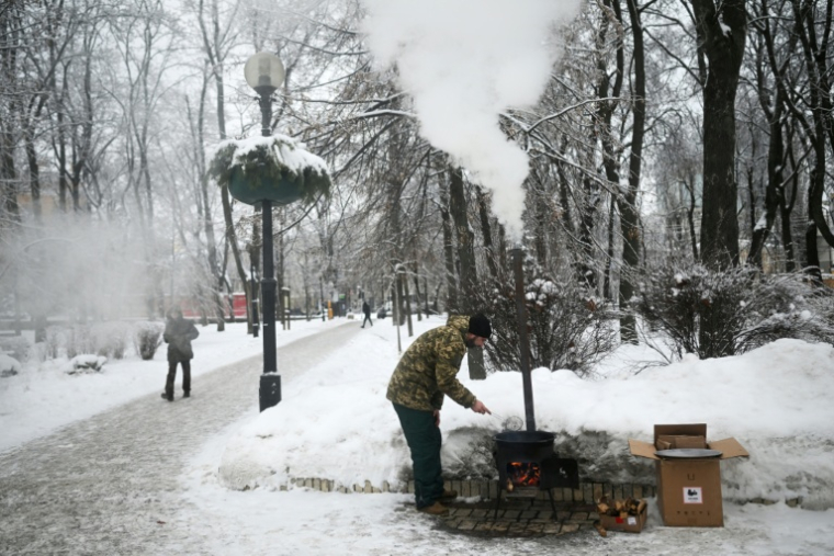 Un bénévole ukrainien cuisine un pain traditionnel d'Asie centrale dans un parc de Kiev, le 15 janvier 2026  ( AFP / Sergei GAPON )