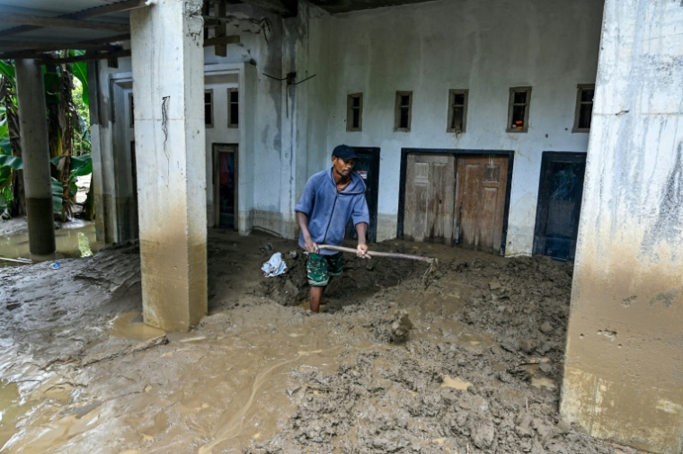 Un homme nettoie l'entrée embourbée d'une maison inondée à Meureudu, dans la province d’Aceh, en Indonésie, le 28 novembre 2025 ( AFP / CHAIDEER MAHYUDDIN )