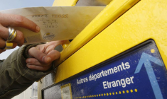 Un homme poste une lettre dans la boîte aux lettres de La Poste à Margaux