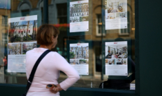 Une passante regarde les annonces immobilières à l'entrée d'une agence à Londres le 18 juin 2026 ( AFP / Toby Shepheard )