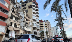 Des voitures passent devant un bâtiment endommagé près de la Corniche, à Tyr