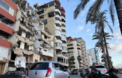 Des voitures passent devant un bâtiment endommagé près de la Corniche, à Tyr