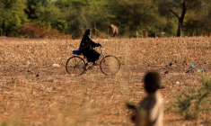 Photo d'archives: Un enfant qui a fui avec ses parents les attaques de militants armés dans la région du Sahel observe une femme à vélo dans un camp de personnes déplacées au Burkina Faso