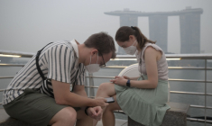 Des touristes portent des masques de protection contre les fumées générées par les incendies indonésiens, le 15 octobre 2026 à Singapour ( AFP / FELINE LIM )