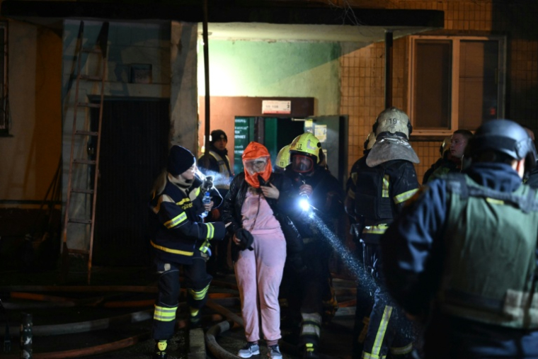 Des pompiers évacuent une femme âgée d'un immeuble touché par une frappe russe à Kiev, le 25 novembre 2025 ( AFP / Genya SAVILOV )