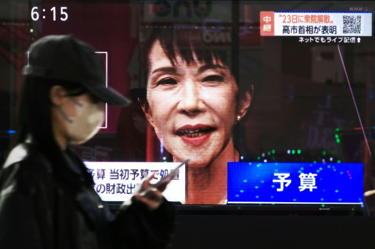 Une femme passe devant un écran de télévision diffusant la conférence de presse de la Première ministre japonaise Sanae Takaichi à Tokyo, le 19 janvier 2026 ( AFP / Kazuhiro NOGI )
