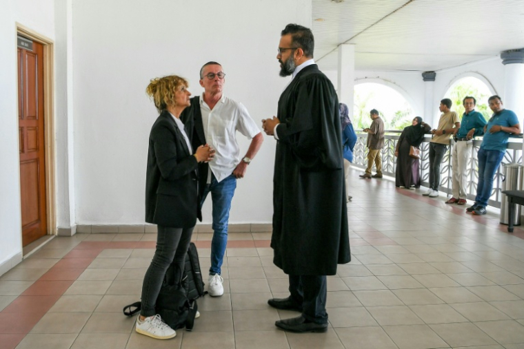 Jean-Luc Felix (au centre) et Sylvie Felix (à gauche), les parents du Français Tom Felix, accusé de détention et trafic de stupéfiants en Malaisie, s'entretiennent avec un avocat à la Haute Cour d'Alor Setar, le 16 juin 2025 ( AFP / Hakim Mustapha )