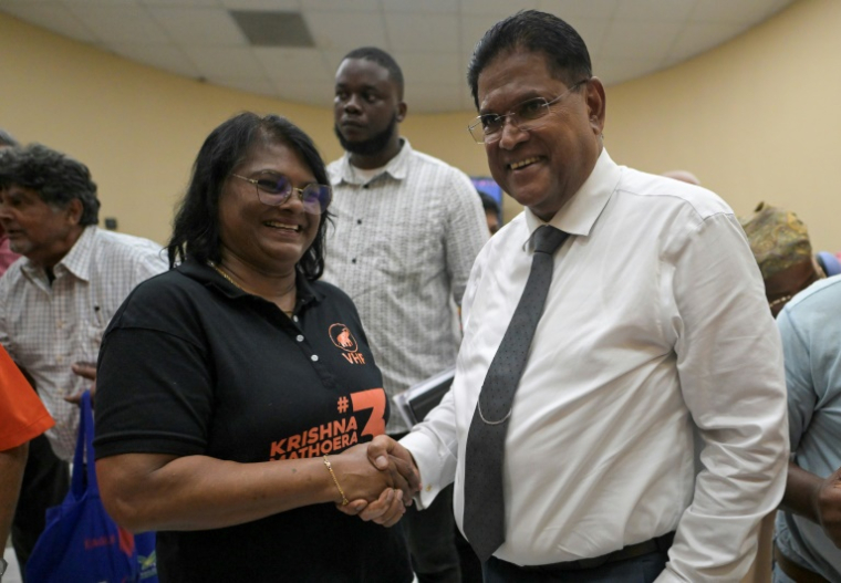 Le président du Suriname, Chandrikapersad Santokhi, serre la main de la ministre de la défense, Krishna Mathoera, après un meeting de campagne de leur parti le VHP à Paramaribo, le 22 mai 2025 ( AFP / Juan BARRETO )