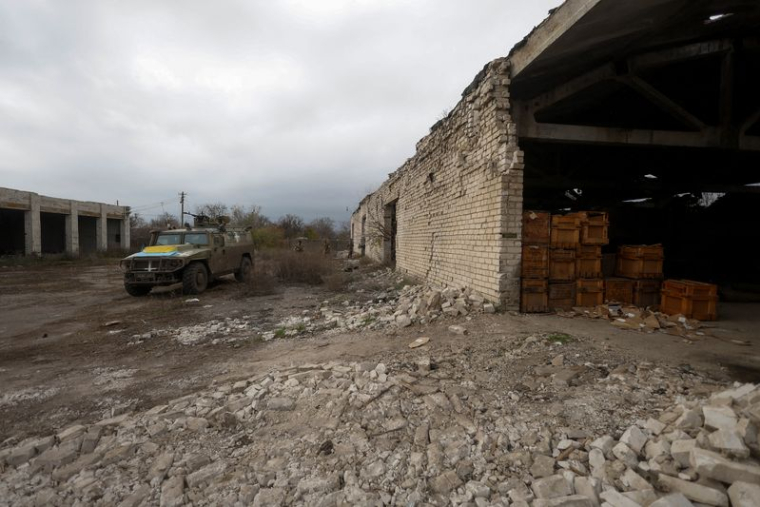Des membres des services ukrainiens marchent vers un véhicule blindé de transport de troupes russe précédemment capturé dans le village de Blahodatne, dans la région de Kherson