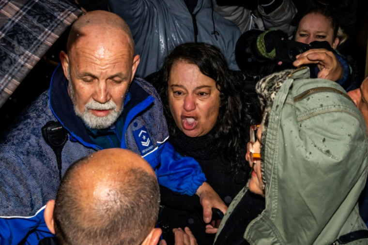 Une mère dont le fils est mort dans l'incendie du bar Le Constellation hurle sa colère devant Jacques Moretti le propriétaire du bar lors de son arrivée au tribunal à Sion, le 12 février 2026 ( AFP / Maxime SCHMID )