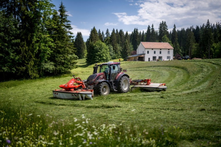 Yannik Melly, un agriculteur installé au pied du massif du Jura et propriétaire d’un champ à cheval sur la France et la Suisse, fauche à Prémanon, le 23 juin 2026 ( AFP / Fabrice COFFRINI )