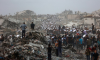 Des Palestiniens, au milieu des décombres sur le chemin côtier de Beit Lahia, dans la bande de Gaza, transportent l'aide alimentaire qu'ils ont pu se procurer le 29 juillet 2025 ( AFP / Omar AL-QATTAA )
